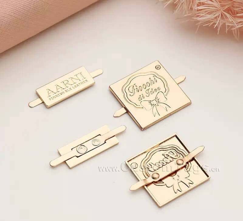 Custom brand metal labels with metal prongs on the back for secure handbag attachment